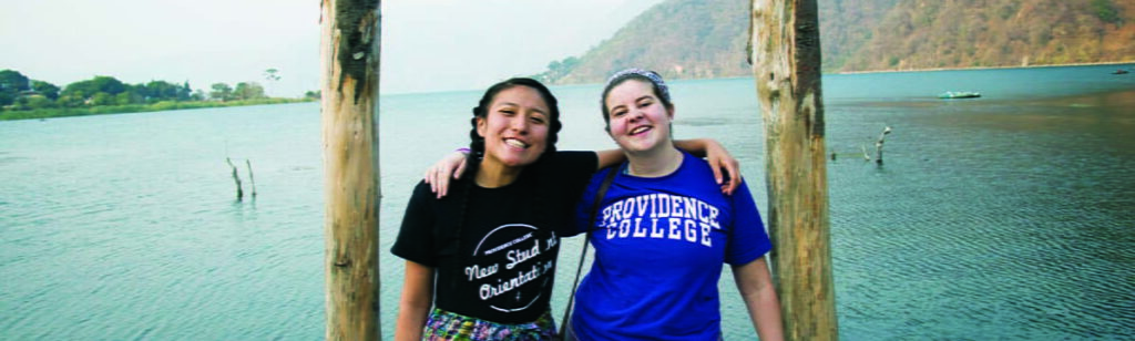 two students in guatemala standing in front of water