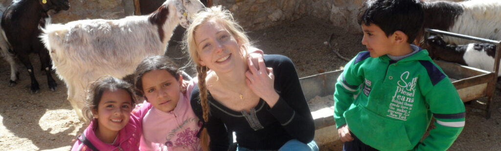 a student with some children sitting in front of a goat